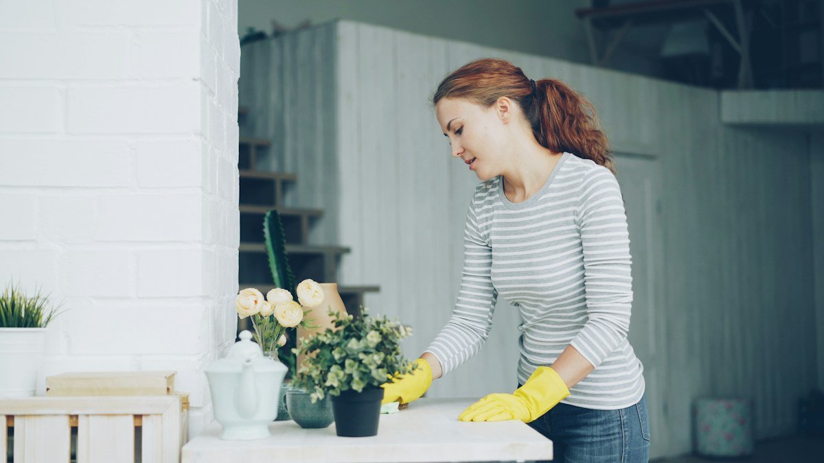 Woman cleaning a table with yellow gloves
